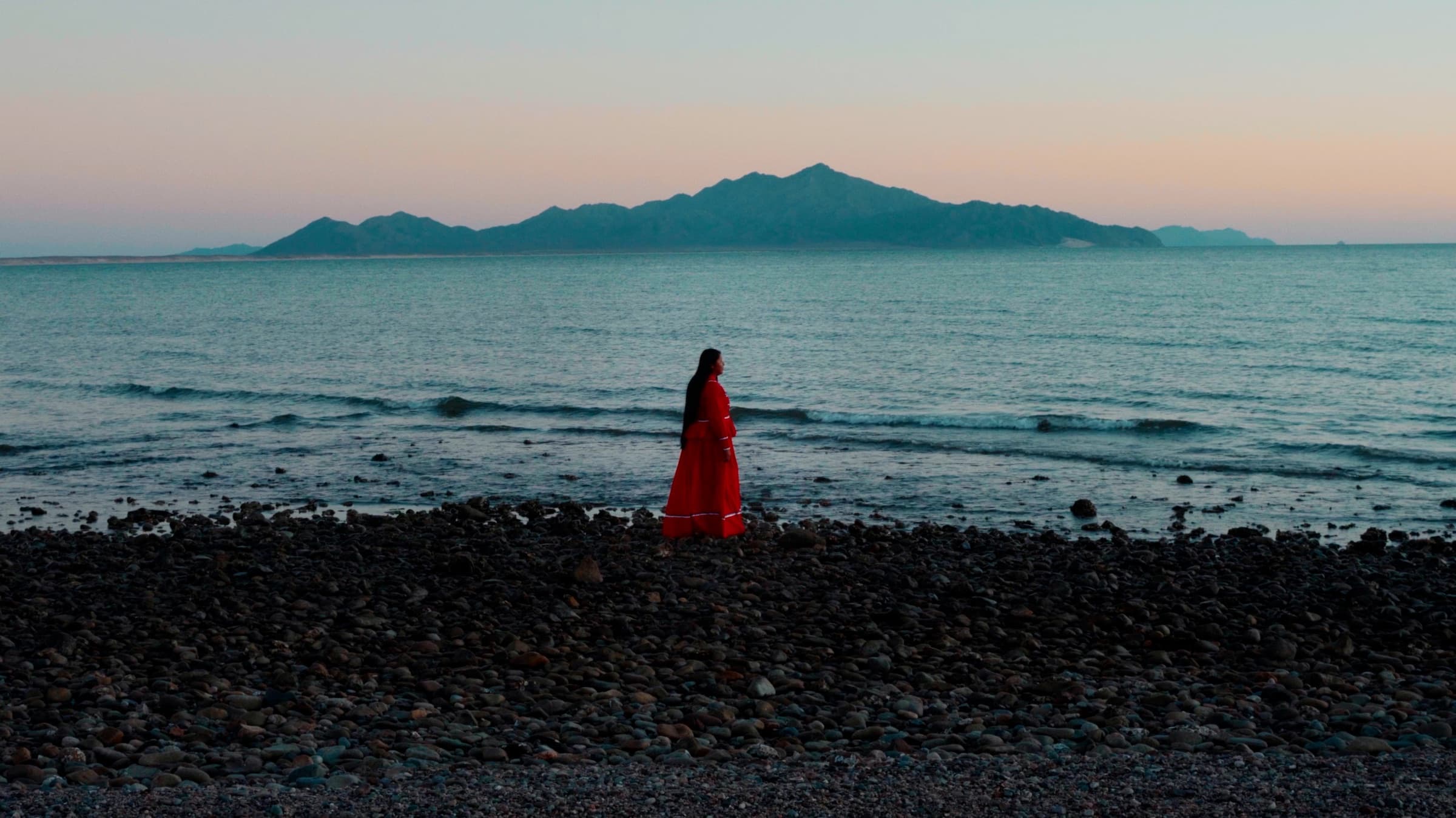 Fotograma del documental: una mujer frente al mar al atardecer